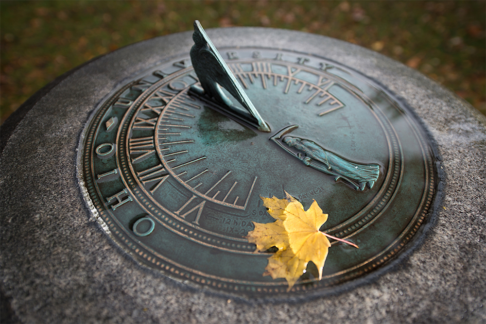 Sundial with leaf falling on it