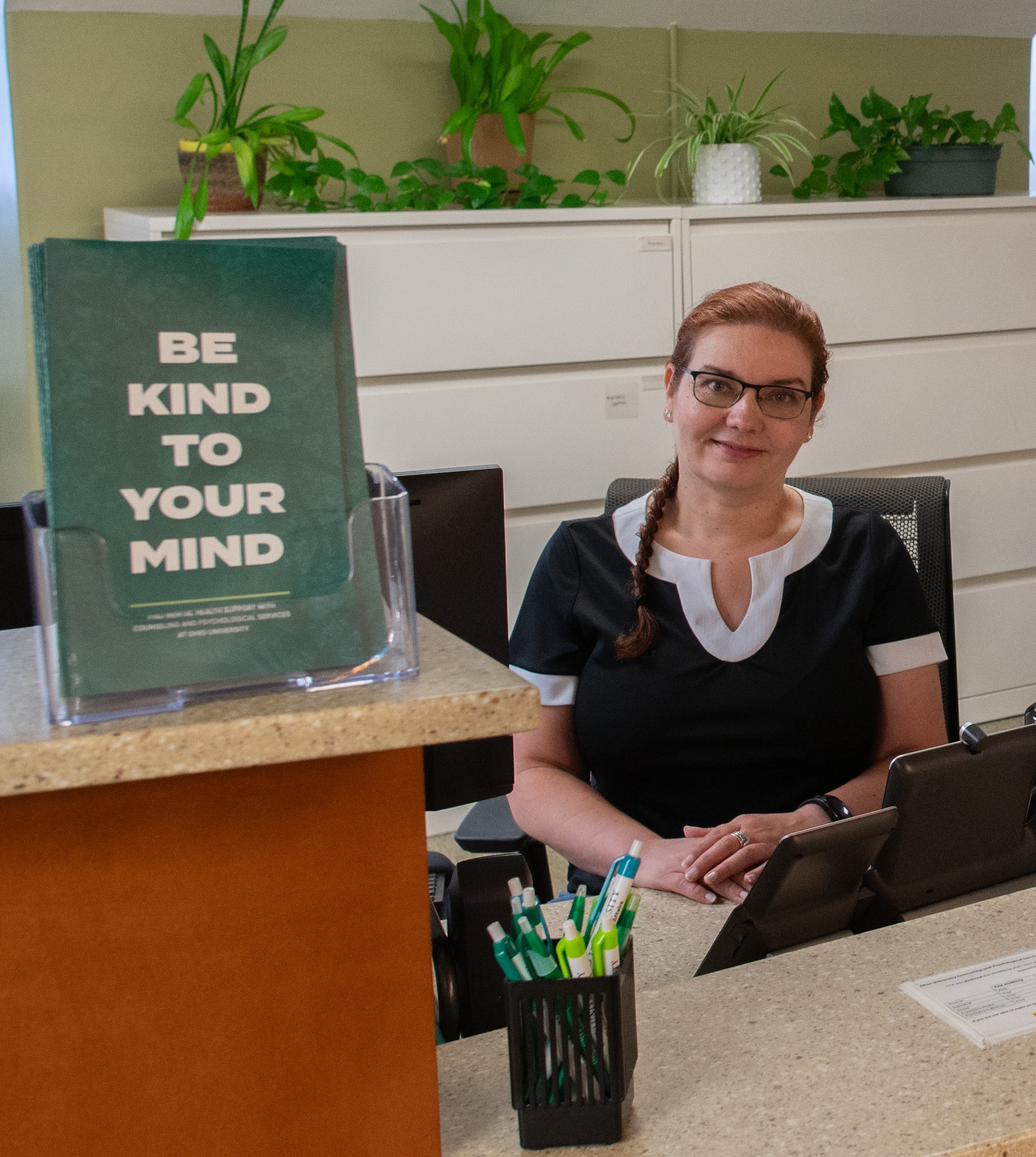 Receptionist at front desk with Be Kind To Your Mind brochure