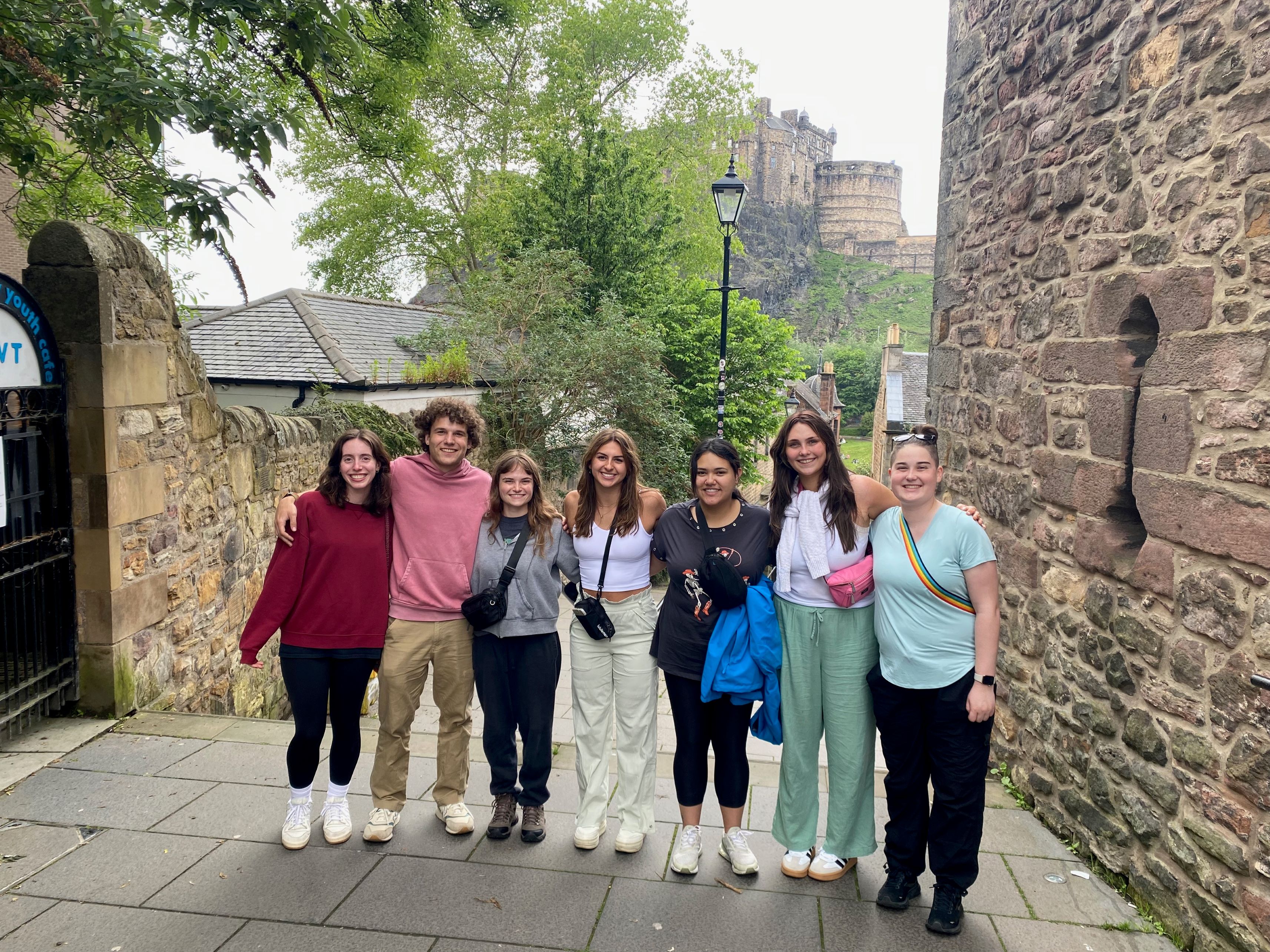 7 students pose together in front of a Scottish Castle.