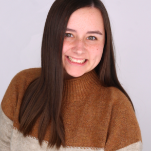 Jaida Carroll stands in front of a white background and smiles at the camera