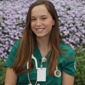 Laurie Littlejohn smiles at the camera, wearing green scrubs and a stethoscope