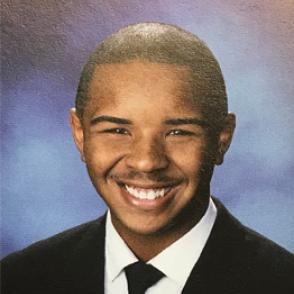 Myles Jay Wortman smiles in a yearbook photo, wearing a suit and tie