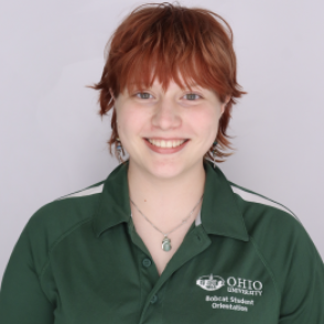 Aria in a dark green Bobcat Student Orientation shirt, smiling at the camera.