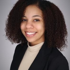 Zaria Jean Bohanan wears a cream shirt and a black blazer, smiling.