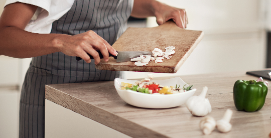 person placing chopped mushrooms into a bowl