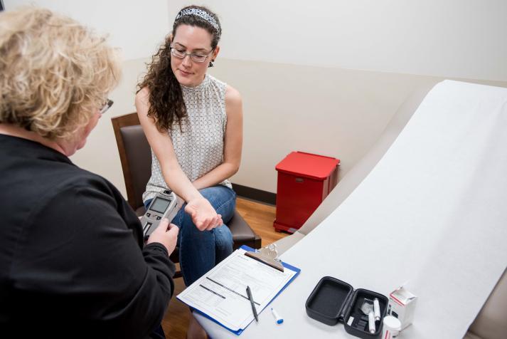 person receiving finger prick for a health screening