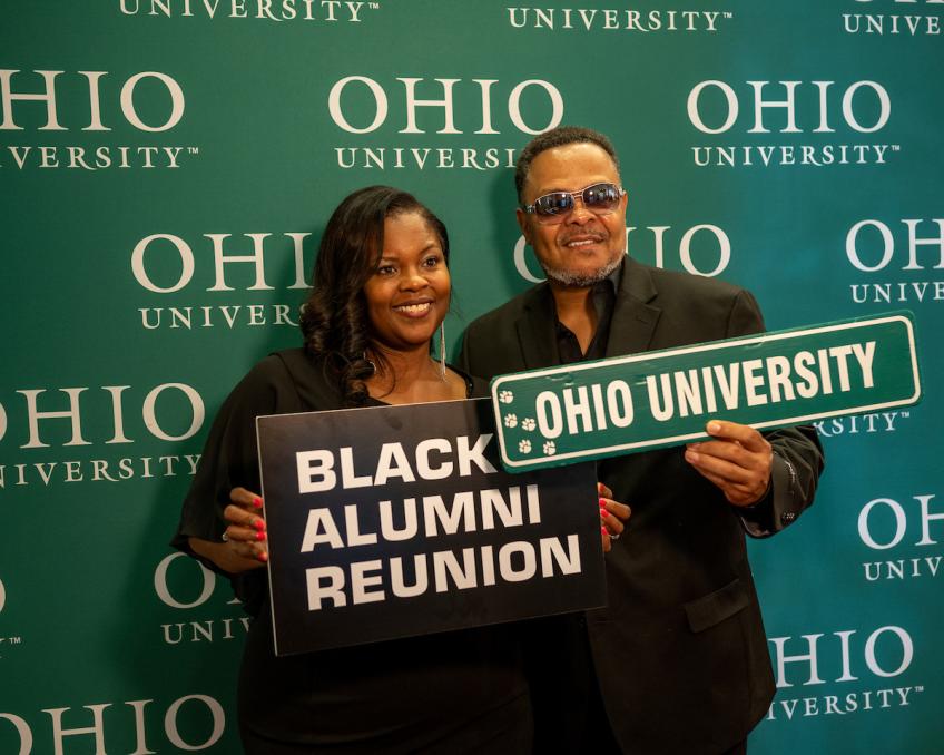 Two people holding signs that say, Black Alumni Reunion, and Ohio University.