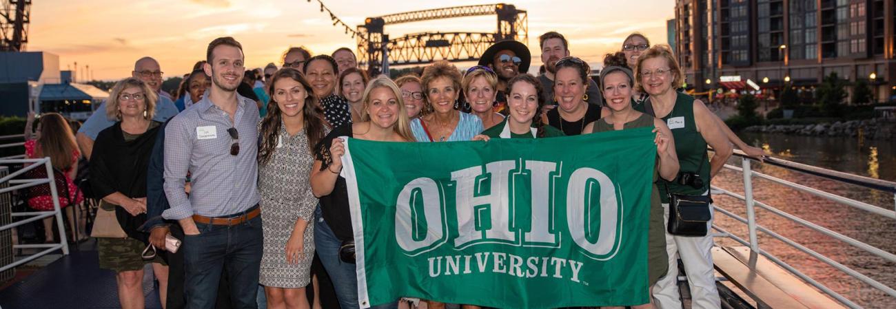 An Alumni Network poses with an Ohio University flag at an event