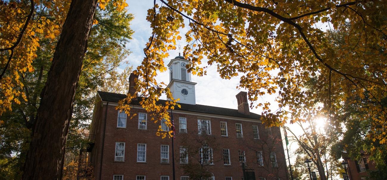 Cutler Hall on Ohio University's Athens campus at sunset, peeking through fall foliage