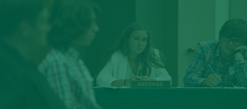 A woman on the defense gazes inquisitively at witness during mock trial. 