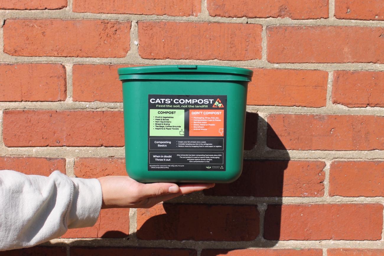 a hand holding a green compost bin