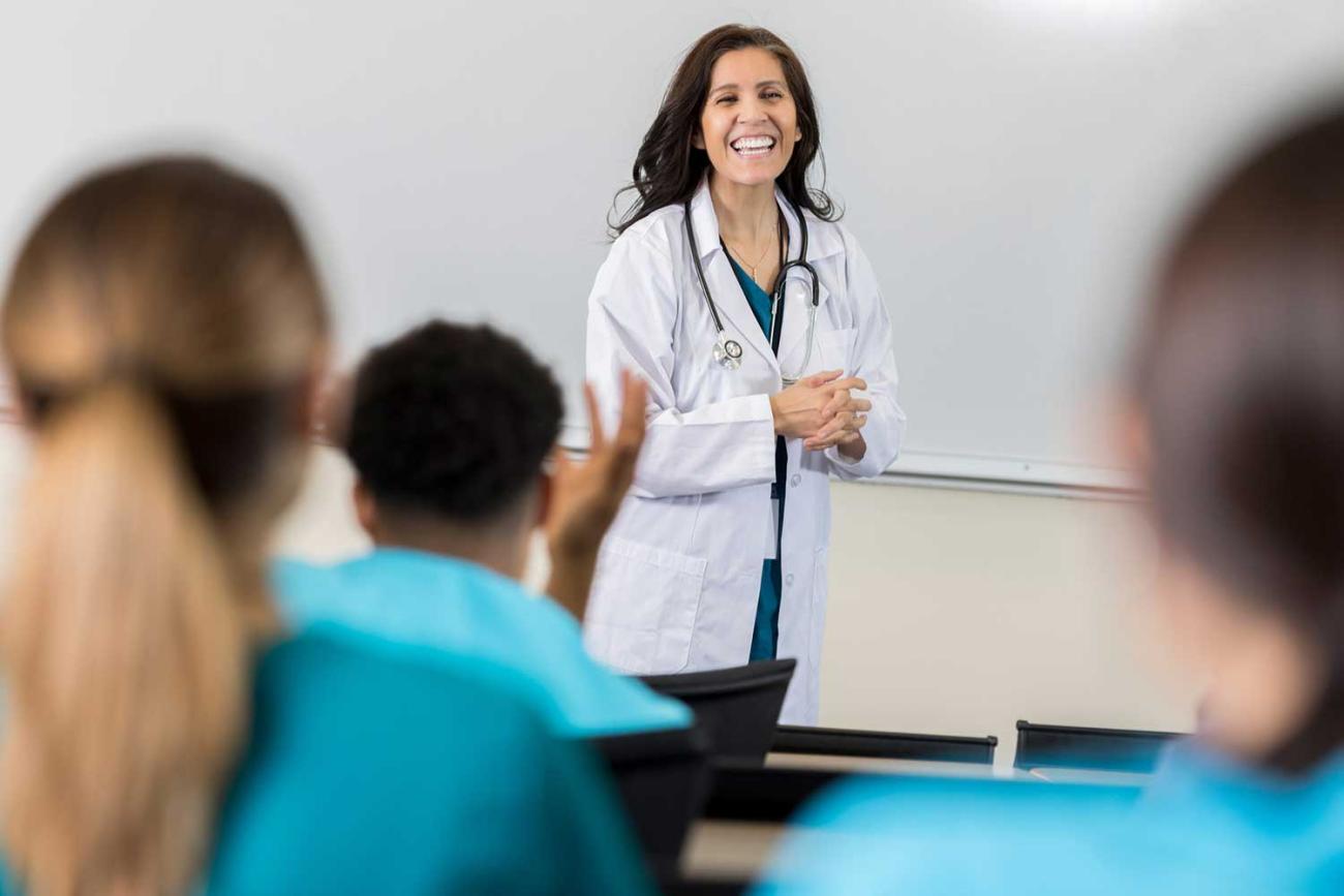 Classroom with female nurse educator at the front of class speaking by white board