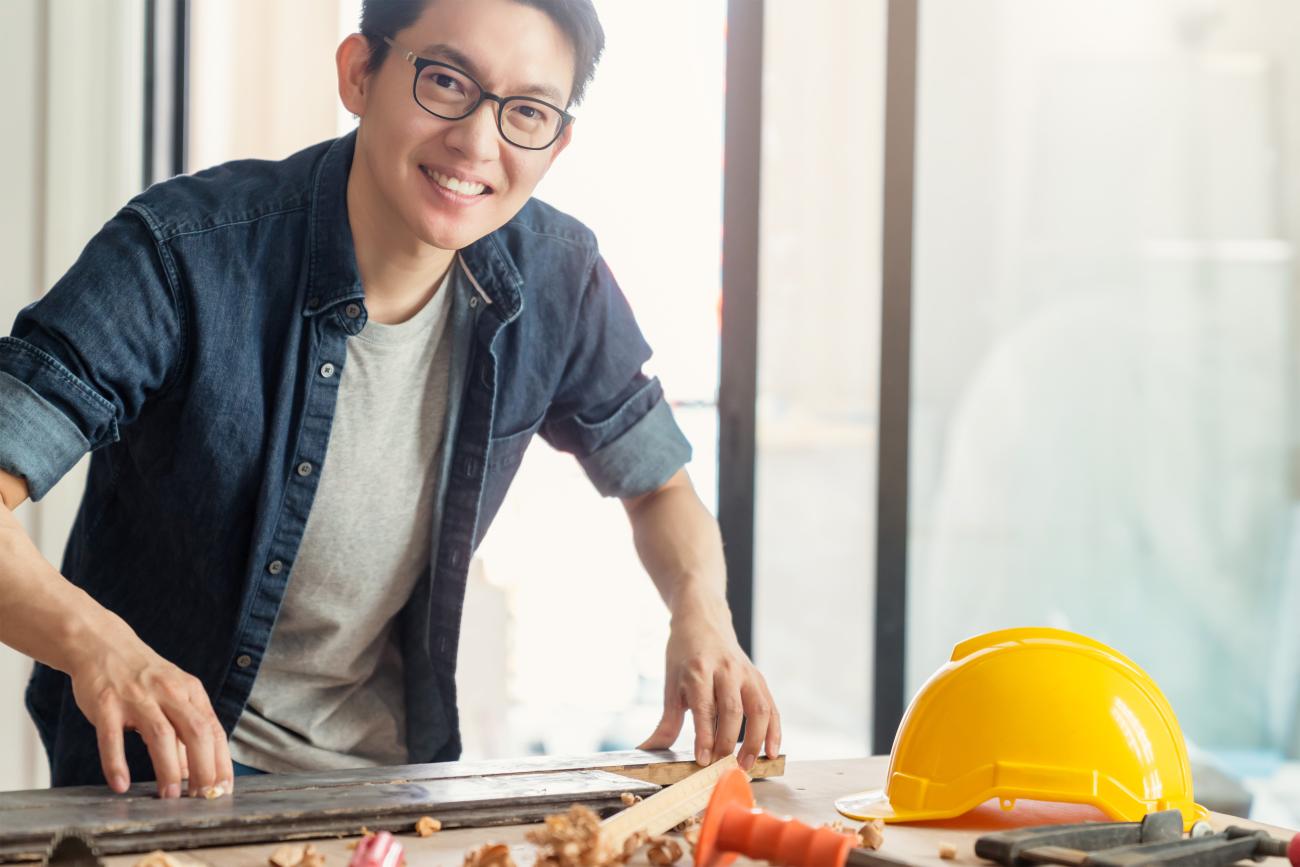 An engineer smiles at the camera while standing over a workbench. Image by Lifestylememory on Freepik.