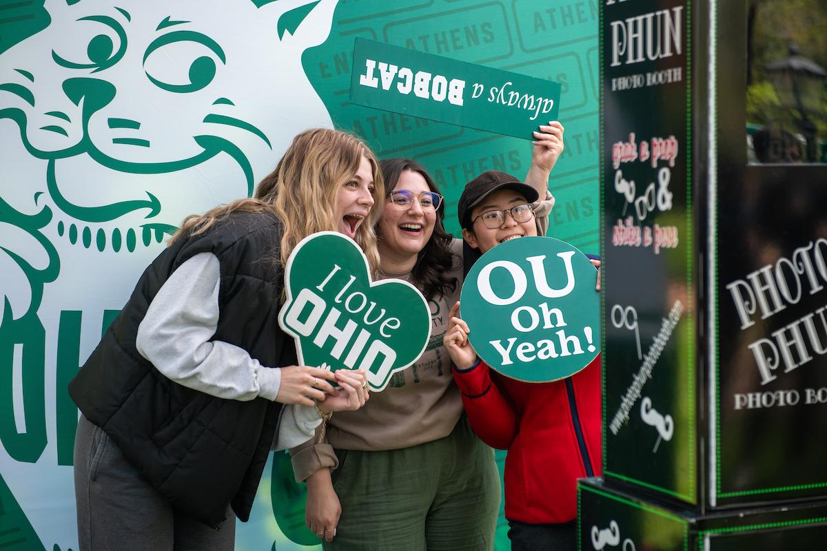 Ohio University students pose in front of a photobooth with props