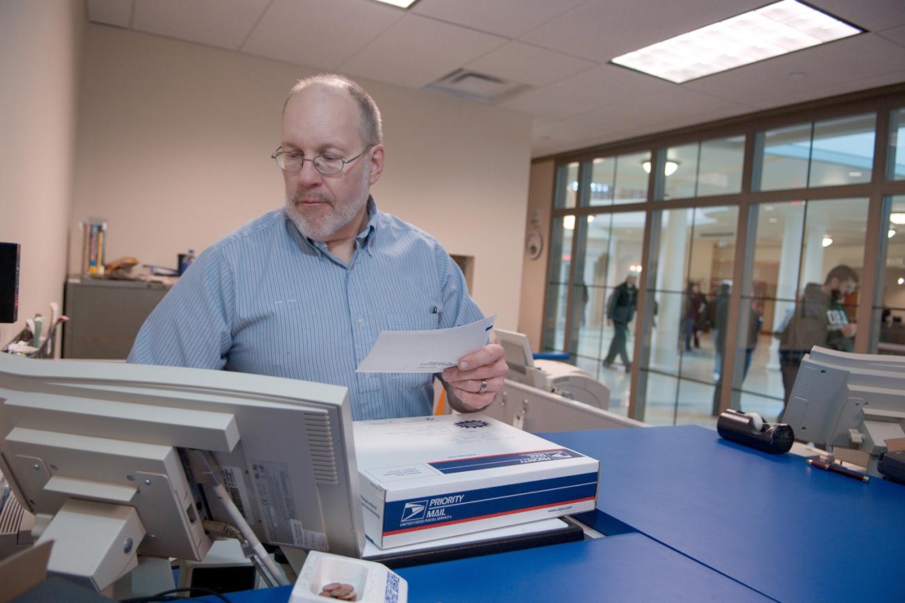 Man inside USPS office in Baker Center