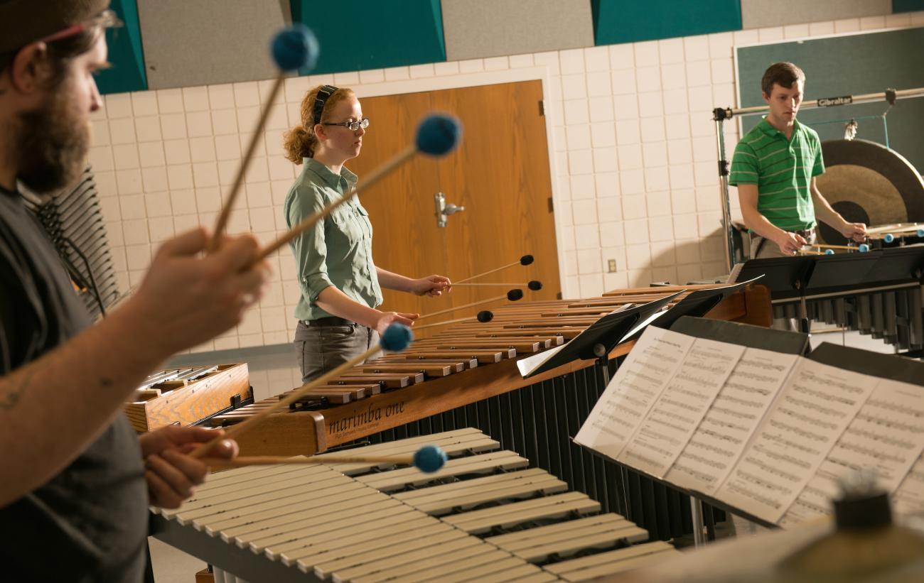 three people playing marimba together