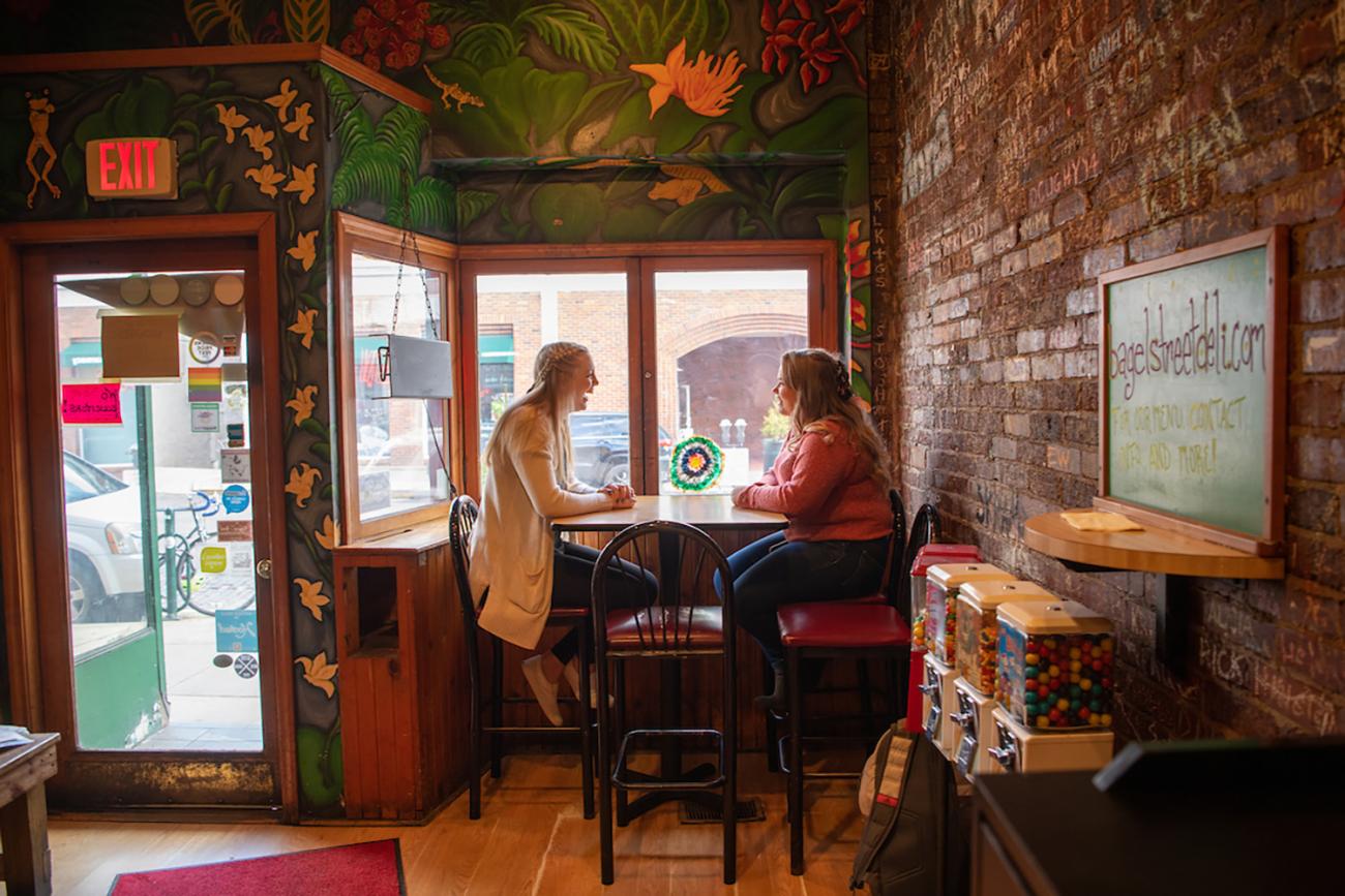 Two girls sitting it a restaurant at a table.