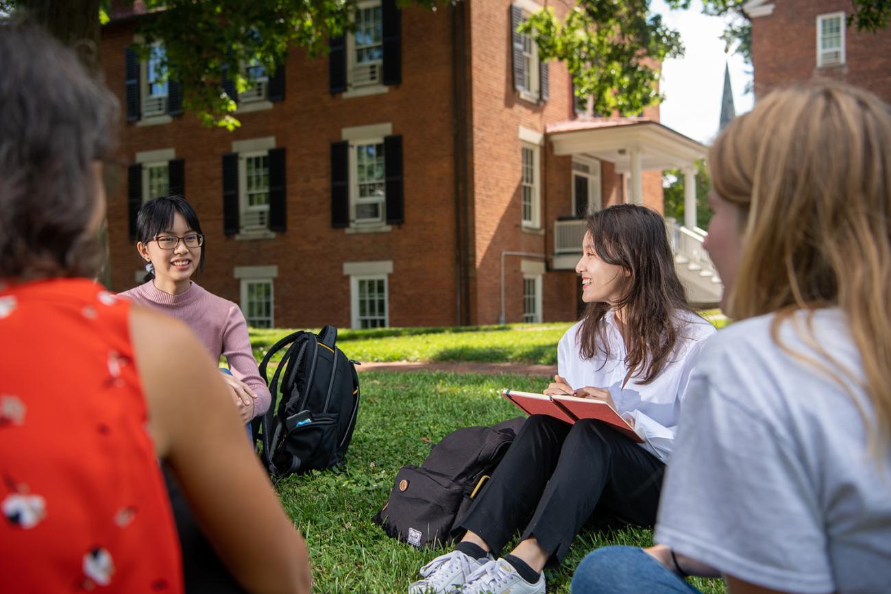 Three International Students Sitting on the Grass Together 