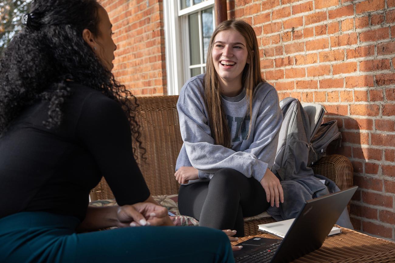 Woman listening to younger student talk sitting on a couch