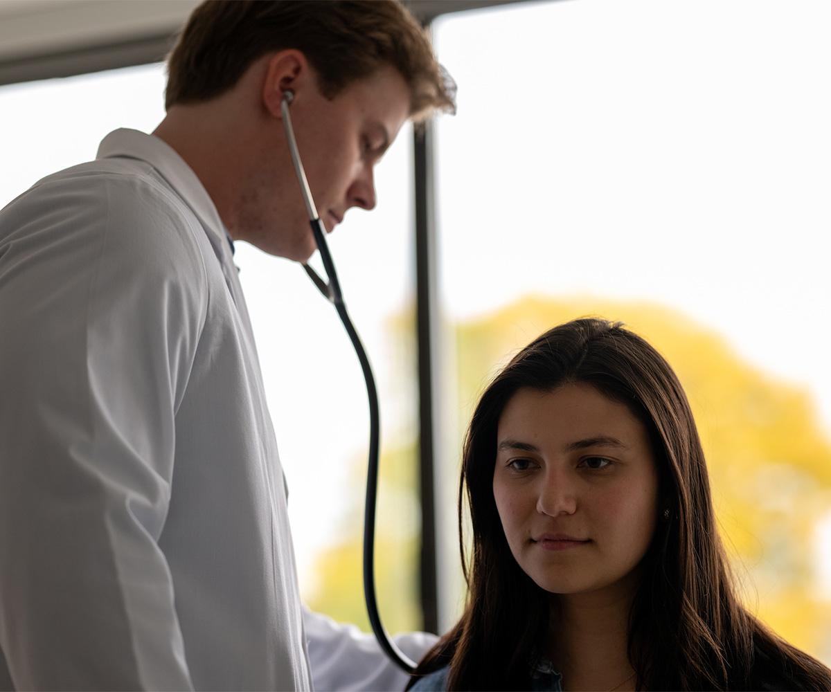 A doctor uses a stethoscope to listen to a patient's lungs.