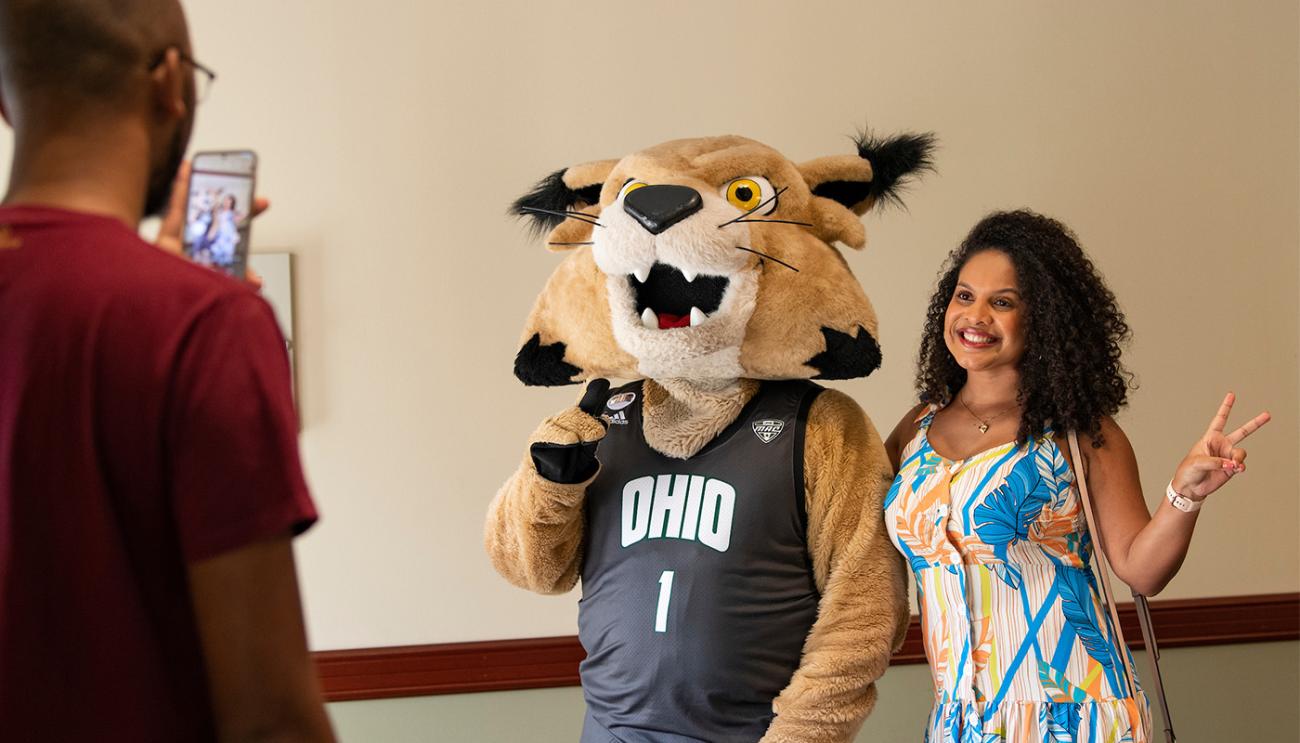 An international student poses for a photo with Rufus the Bobcat.