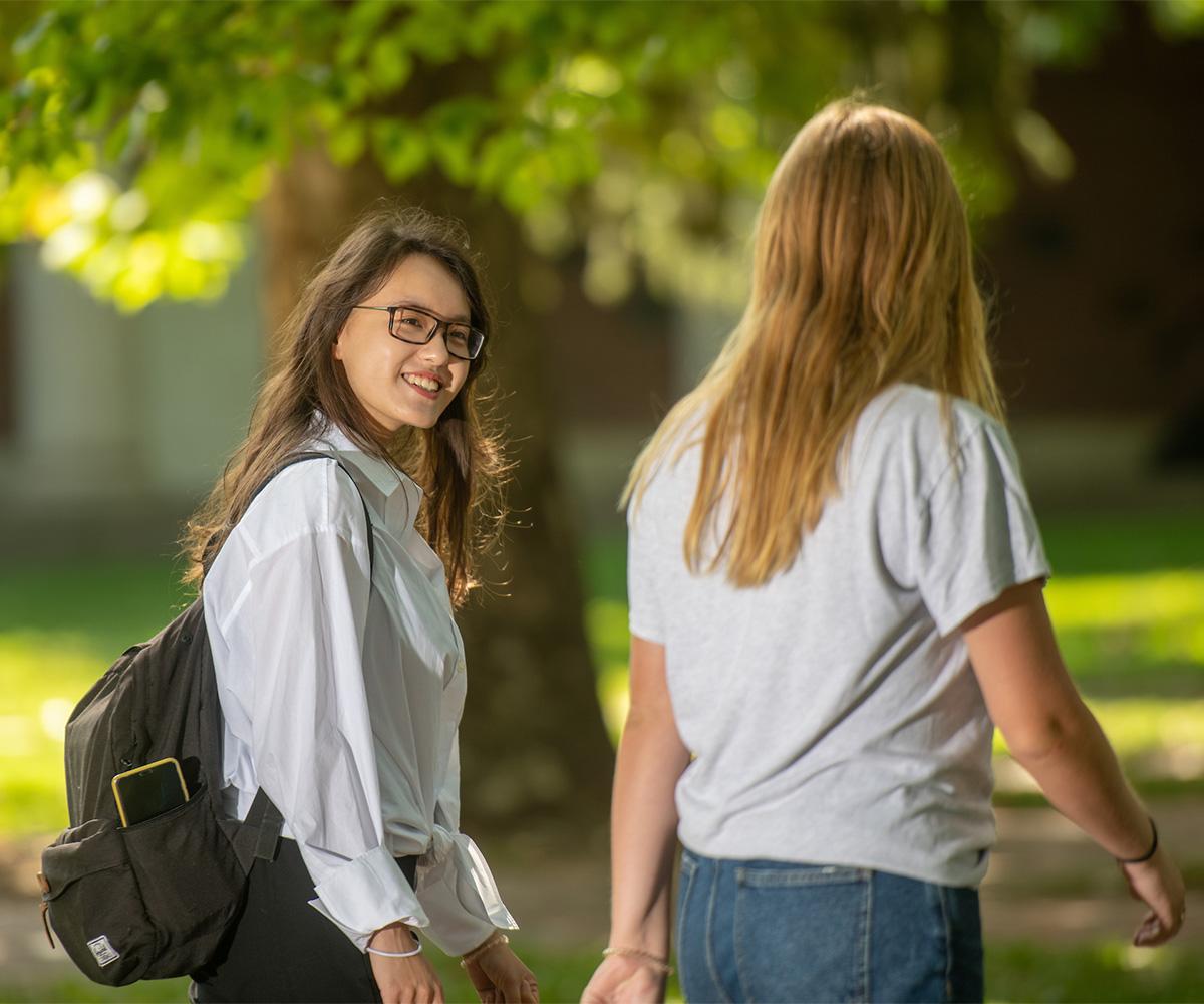 Two international students talk as they walk through campus.