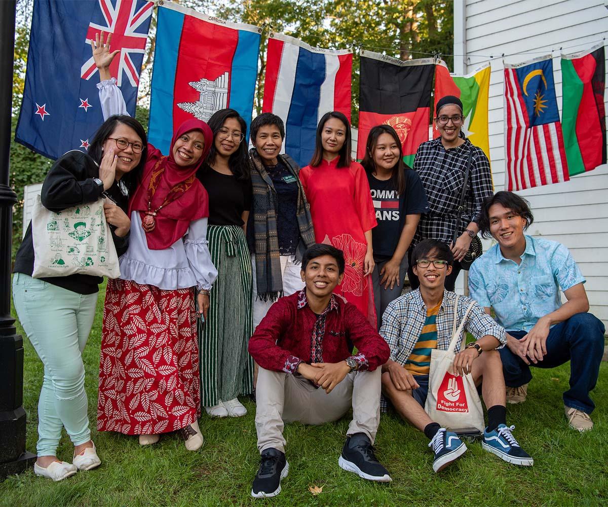 International students pose for a photo at a dinner in front of a flag backdrop.