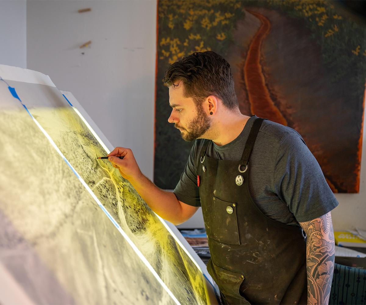 A student sketches on a drawing table.