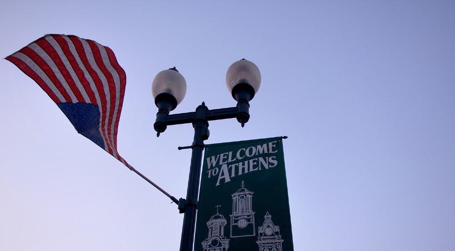 American flag waving in wind by Athens city sign