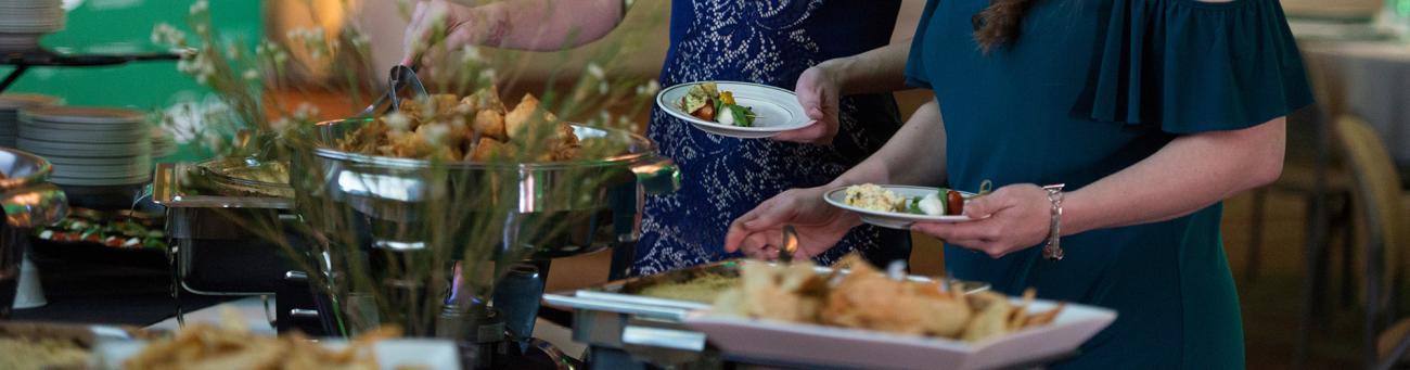 Closeup of people serving themselves at an OHIO Catering buffet table