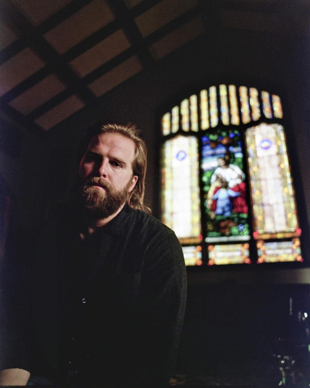 Charles Wesley Godwin headshot with stained glass window in background