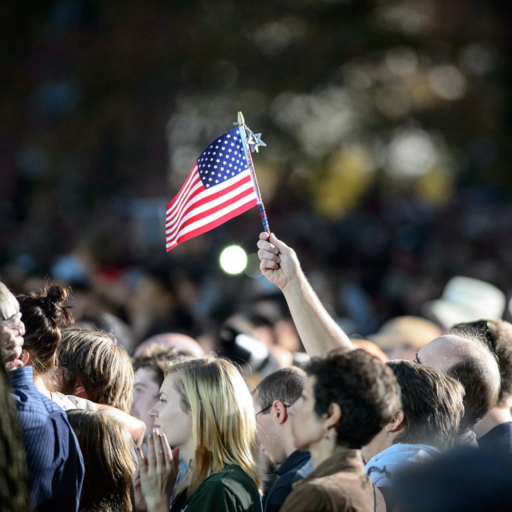 Students stand together, with one holding an American flag above the crowd