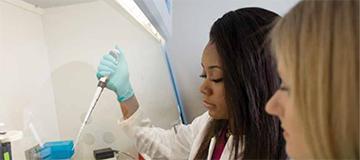 Scene of two students in a lab setting using a pipette