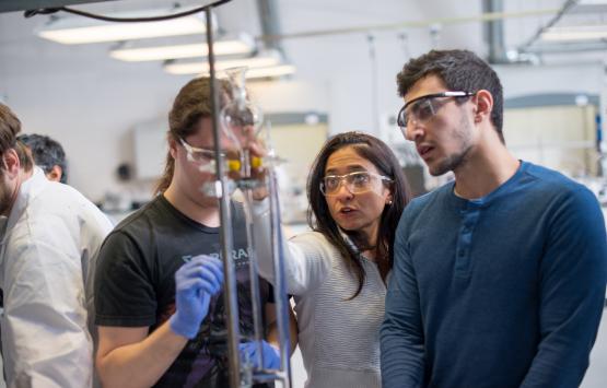 A professor helps students in a laboratory setting