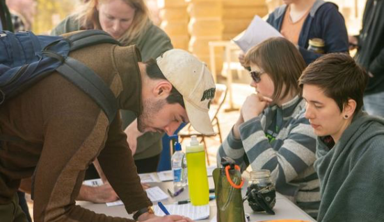 Guy signing a document outside