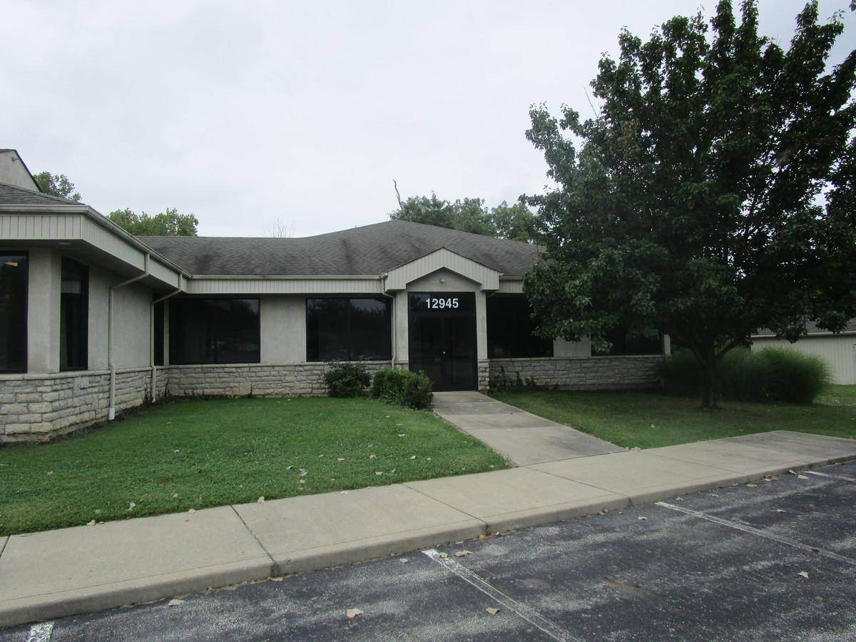 1-story commercial building with tinted windows, the address 12945 prominently on the tinted door, and a sidewalk leading to an asphalt parking lot with marked spaces