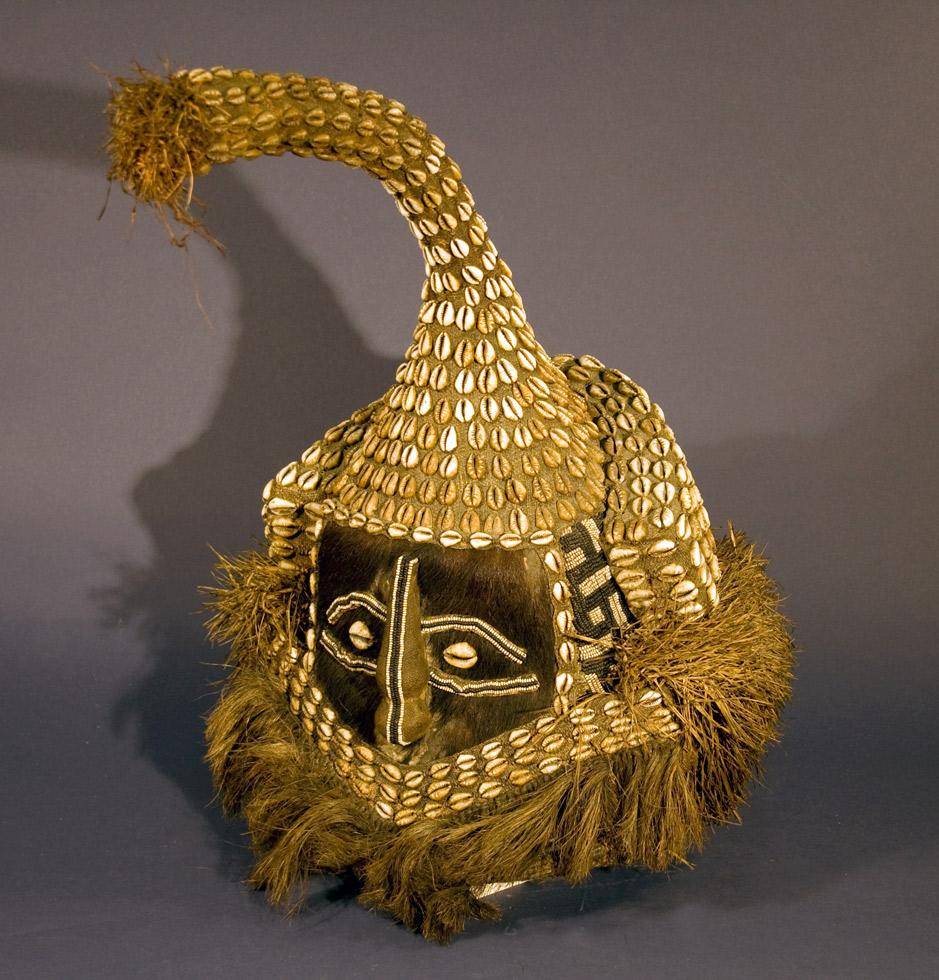 Moshambwooy (or Mukenga) Mask,  20th c. Kuba, Democratic Republic of Congo, wood, raffia, shell, fabric, fur, 21 x 10.5 x 15in (53.3 x 26.7 x 38.1cm), 83.066.B6.