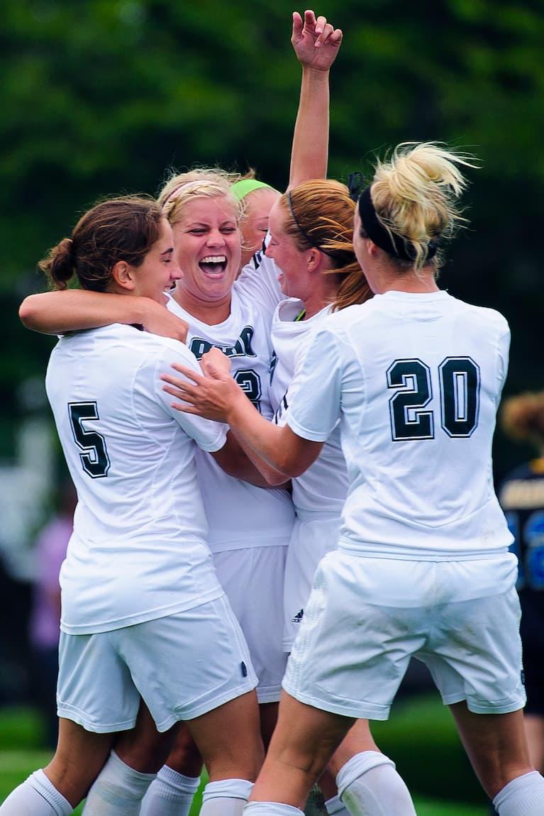Members of the Ohio University women's soccer team celebrate together on the field