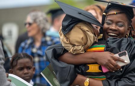 Recent graduate at commencement hugging their supporter