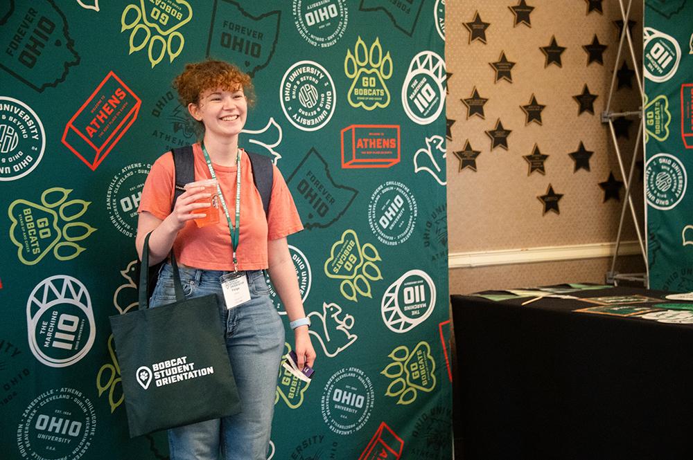 A new student poses in front of a photo booth backdrop at BSO