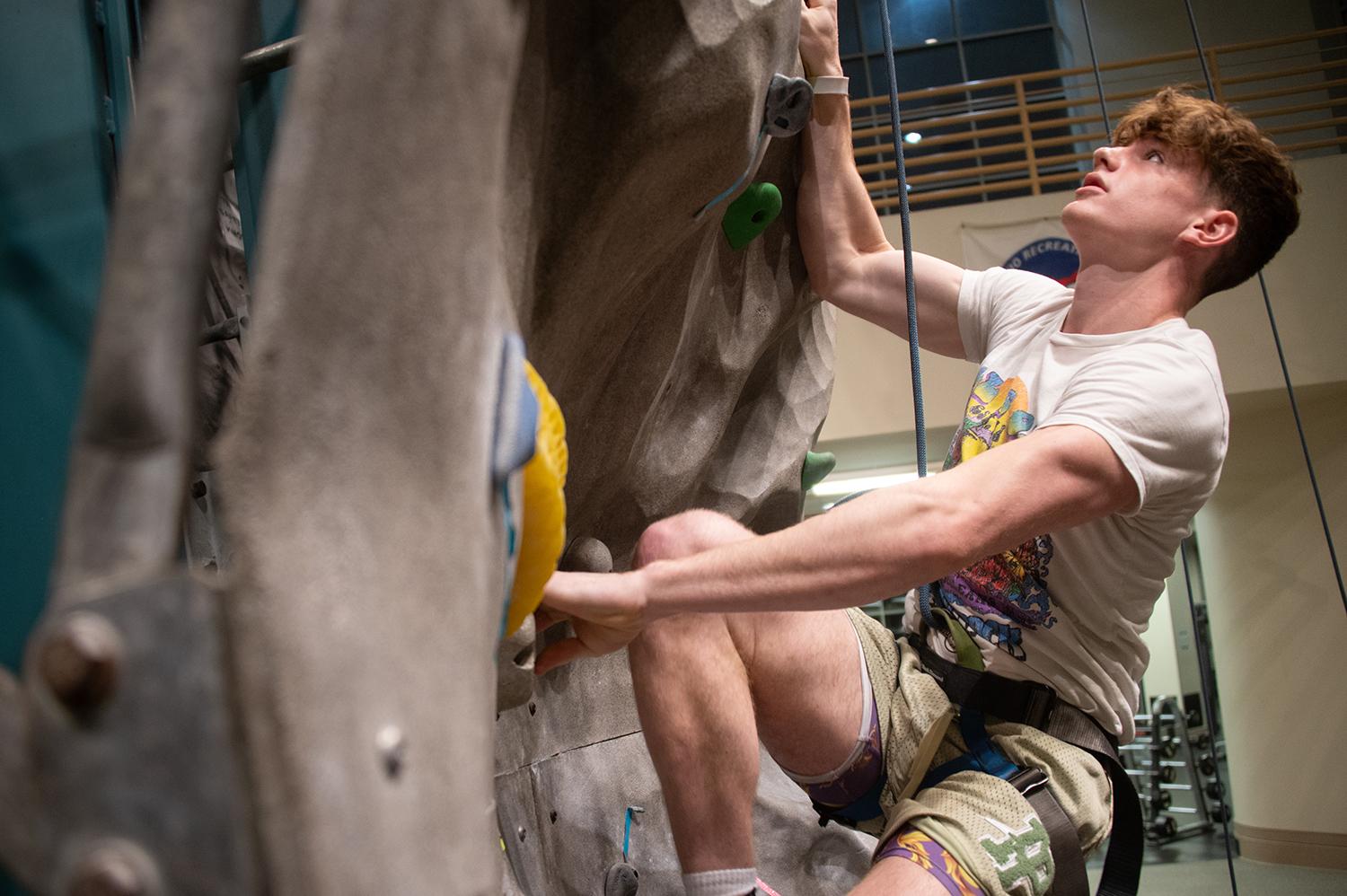 A new student climbing a rock wall at Ping Center during BSO