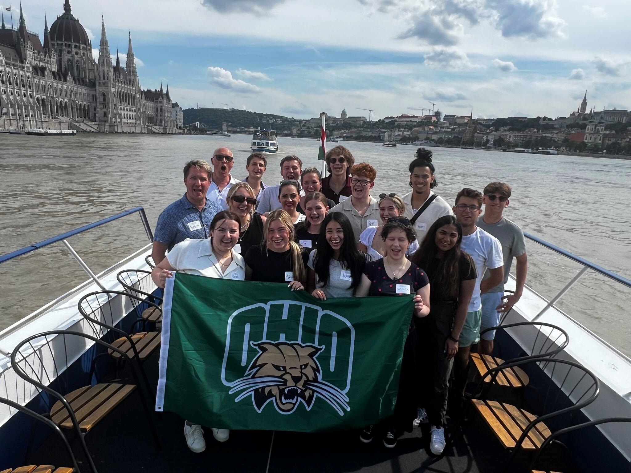 Group photo on a boat holding green OHIO flag with Attack Cat.