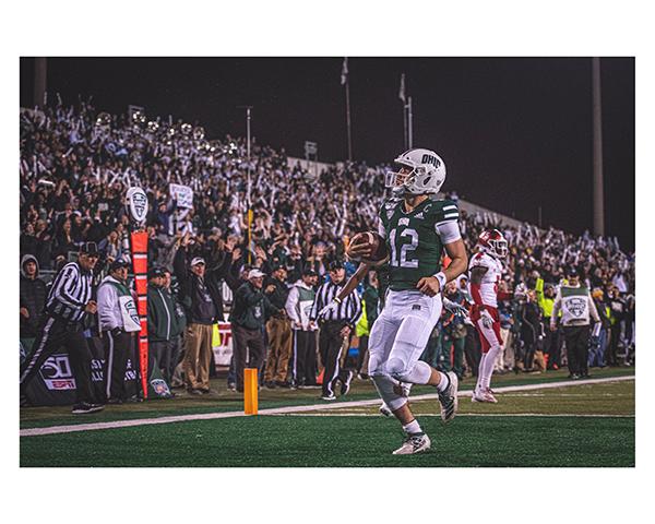 An Ohio University football player runs up the field in front of a large crowd at the OHIO vs. Miami game on Wednesday, November 6, 2019.