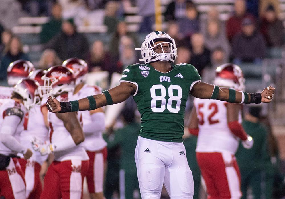 A football player holds his arms out in celebration during a game against Miami.