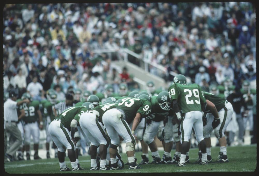 Ohio University football players huddle together during a game in 1990.