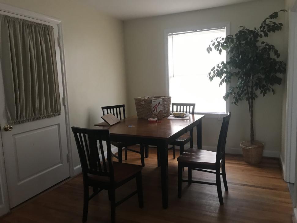 Dining area with table seating four, door with curtain over its window, and an outside window