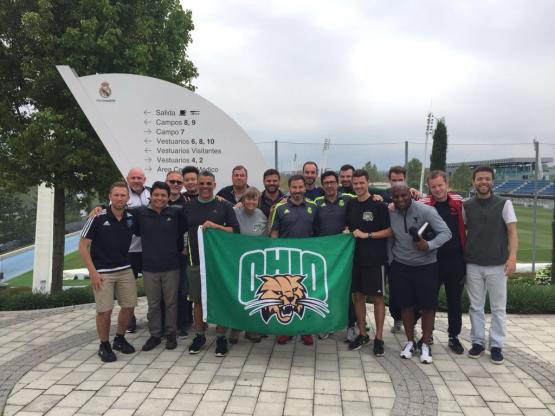 Group photo holding OHIO University flag with Bobcat.