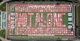 The Monument Quilt on display at Peden Stadium, spelling out "Not Alone" and featuring over 2,000 quilt squares.