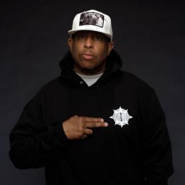 Headshot of DJ Premier wearing a black hoodie and white hat