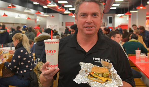 Samuel Chamberlain holding up a Five Guys burger and drink